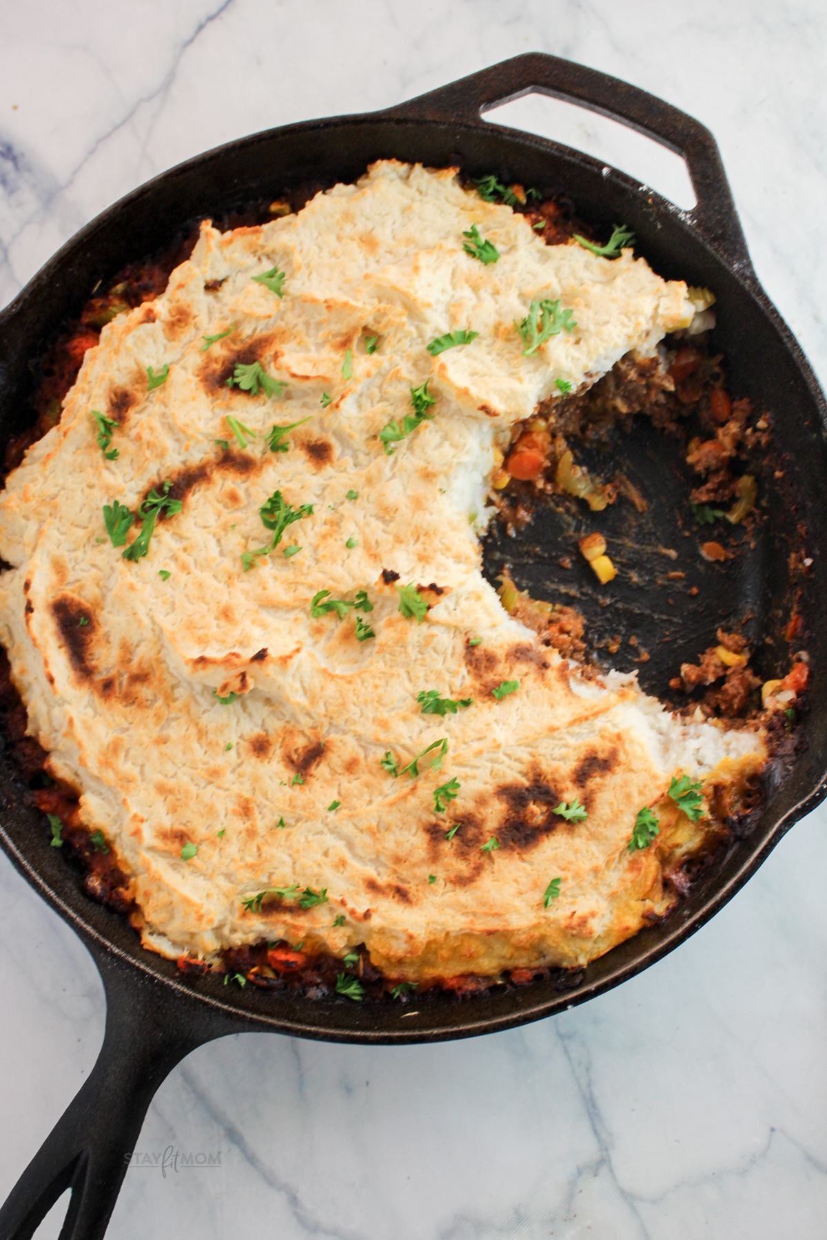 Macro-friendly Shepherd’s Pie baked until golden brown with creamy mashed potato topping and hearty beef filling in a black casserole dish.