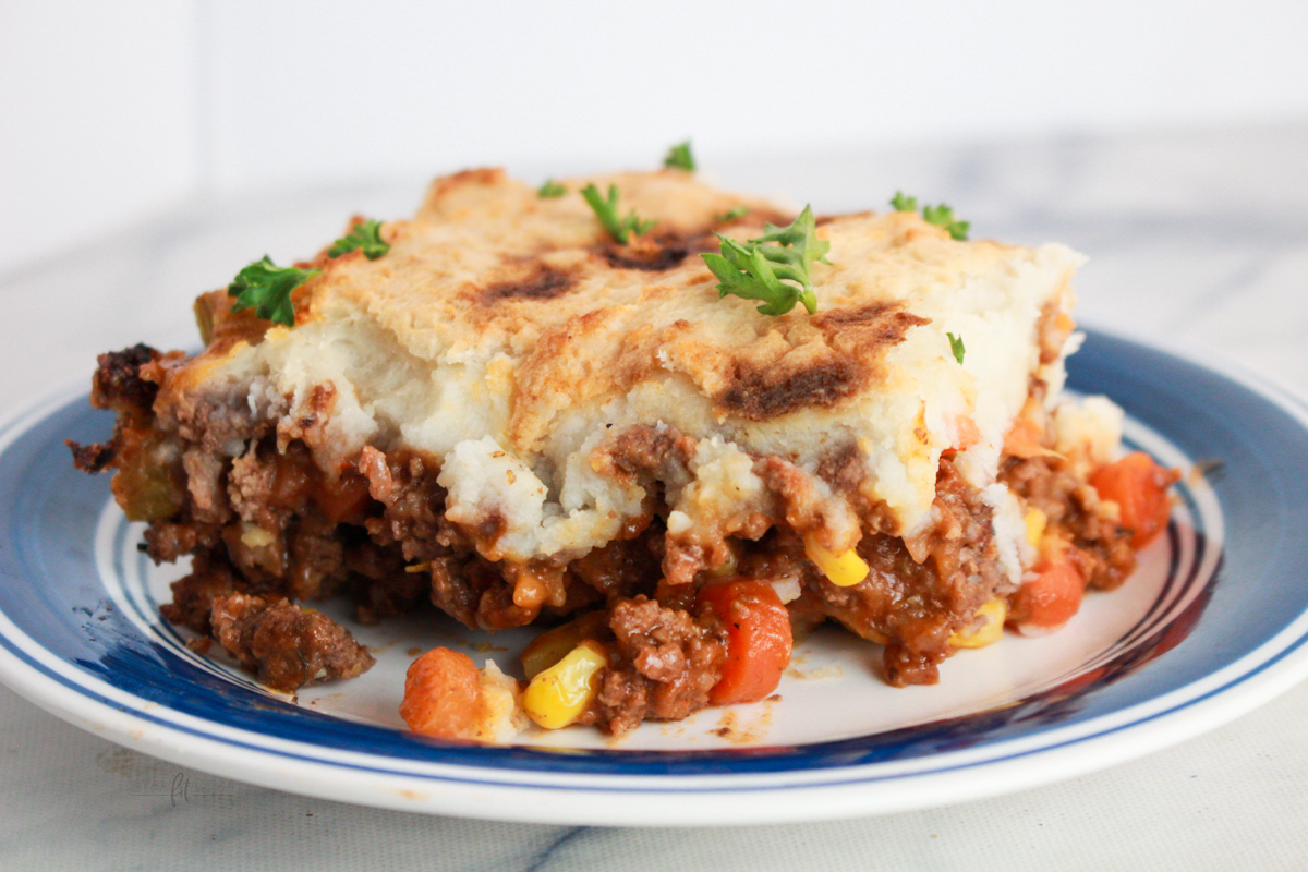 Macro-friendly Shepherd’s Pie baked until golden brown with creamy mashed potato topping and hearty beef filling in a black casserole dish.