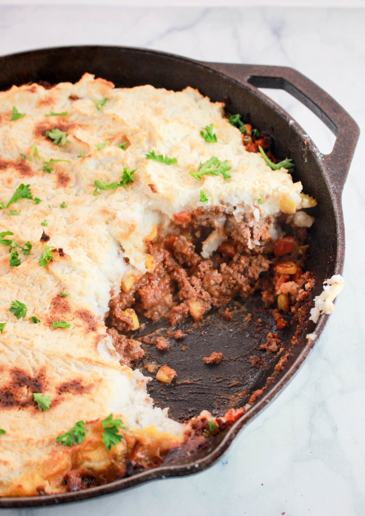 Macro-friendly Shepherd’s Pie baked until golden brown with creamy mashed potato topping and hearty beef filling in a black casserole dish.