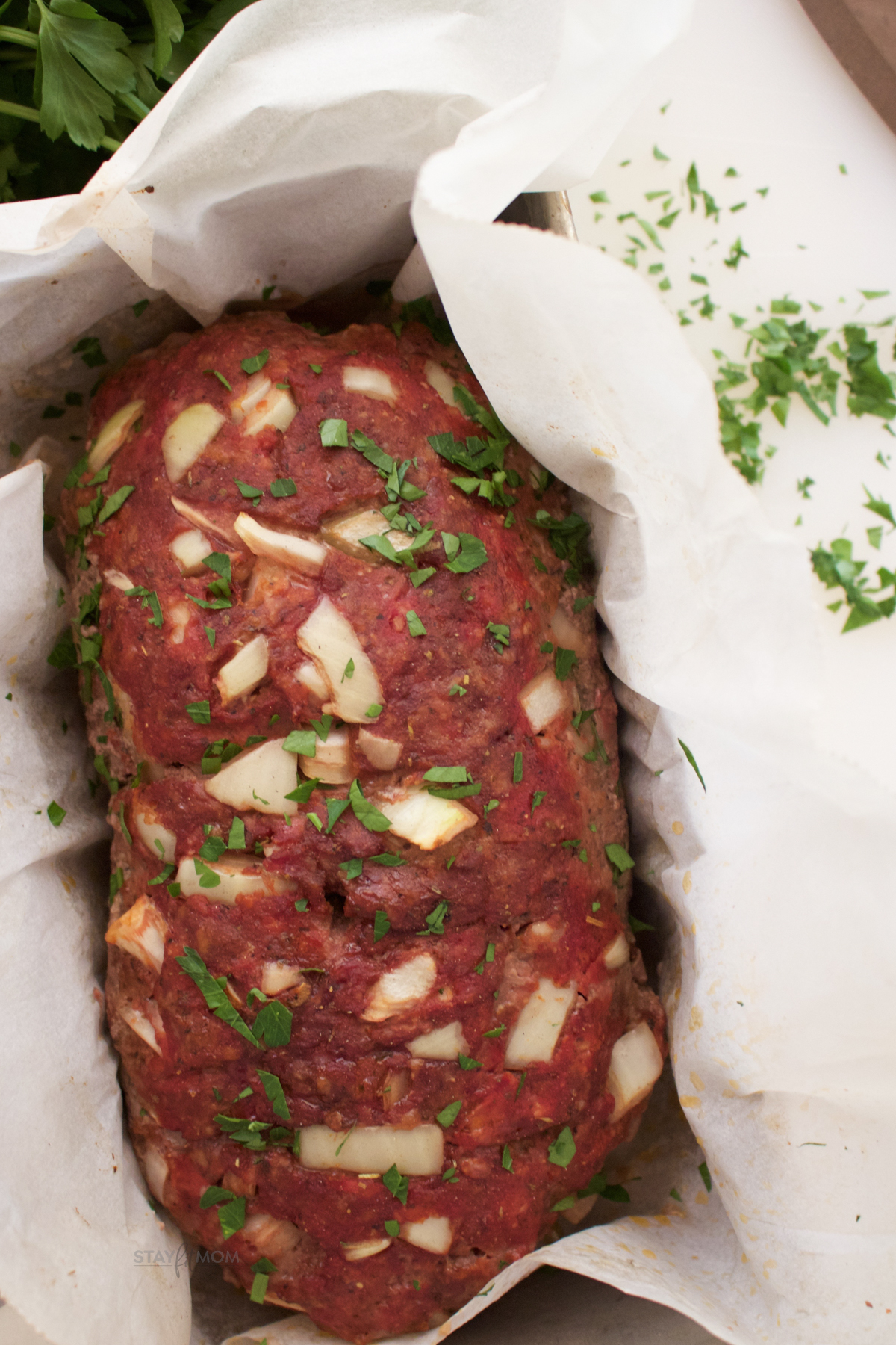 finished meatloaf with onions and parsley on top.