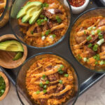 bang bang chicken meal prep in glass bowls with avocado and red pepper flakes.