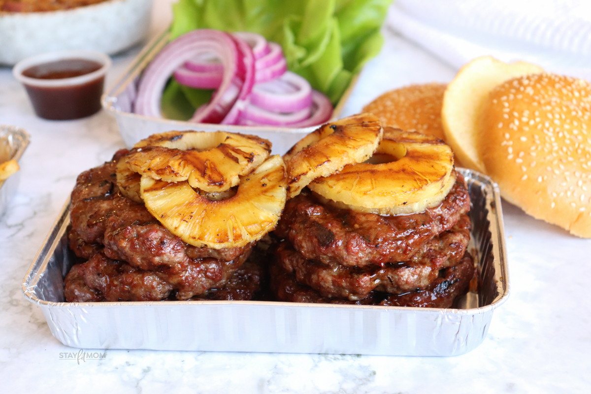 Teriyaki burgers in a pan topped with grilled pineapple.