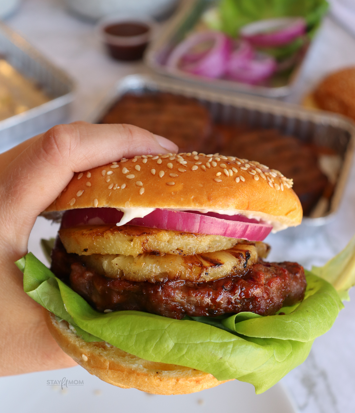 Teriyaki Burger on a bun with visible grilled burger topped with pineapple, lettuce, onions.