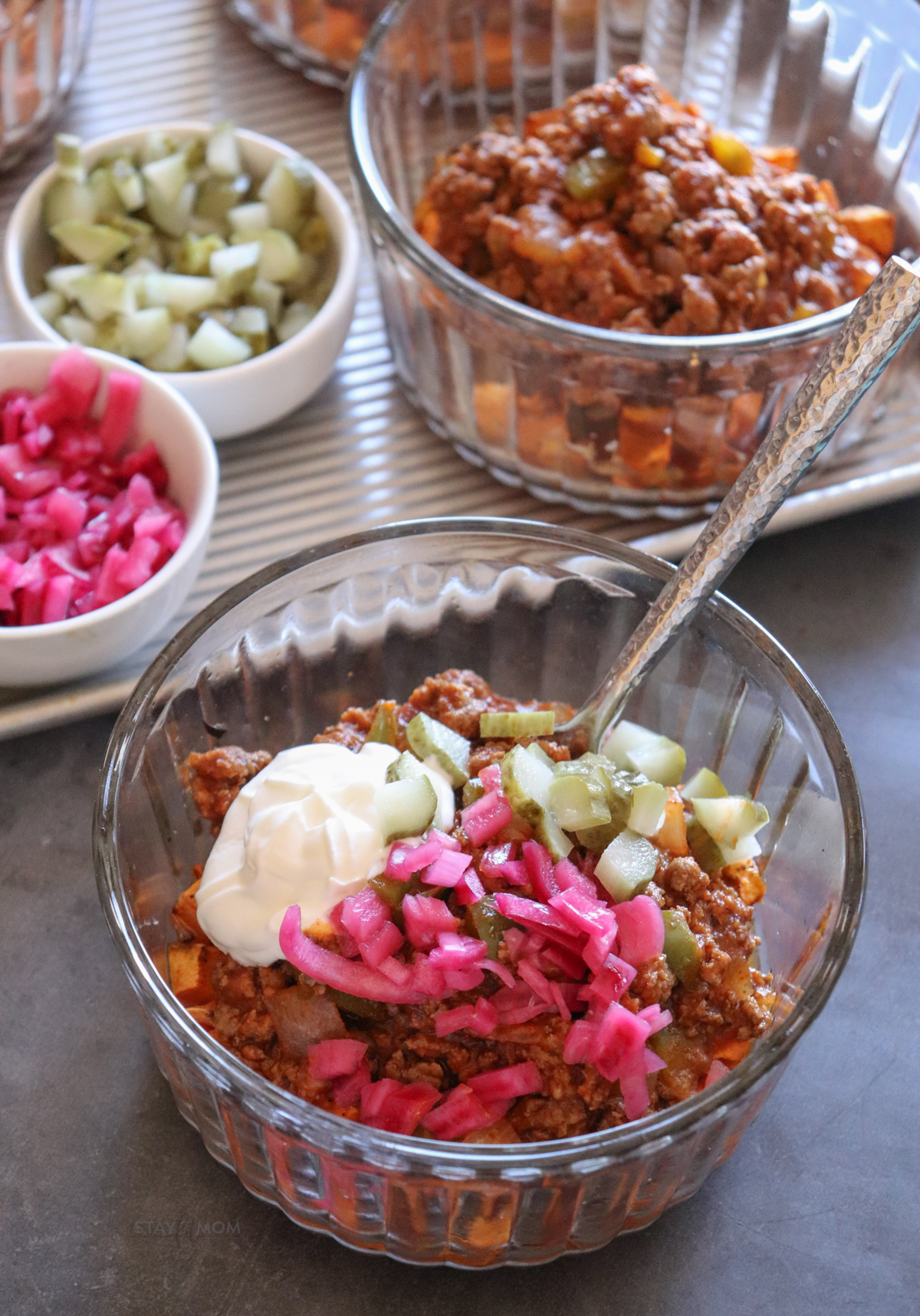 Sloppy Joe Bowls with visible sweet potato, ground beef mixture, greek yogurt, diced pickles, and pickled onions.