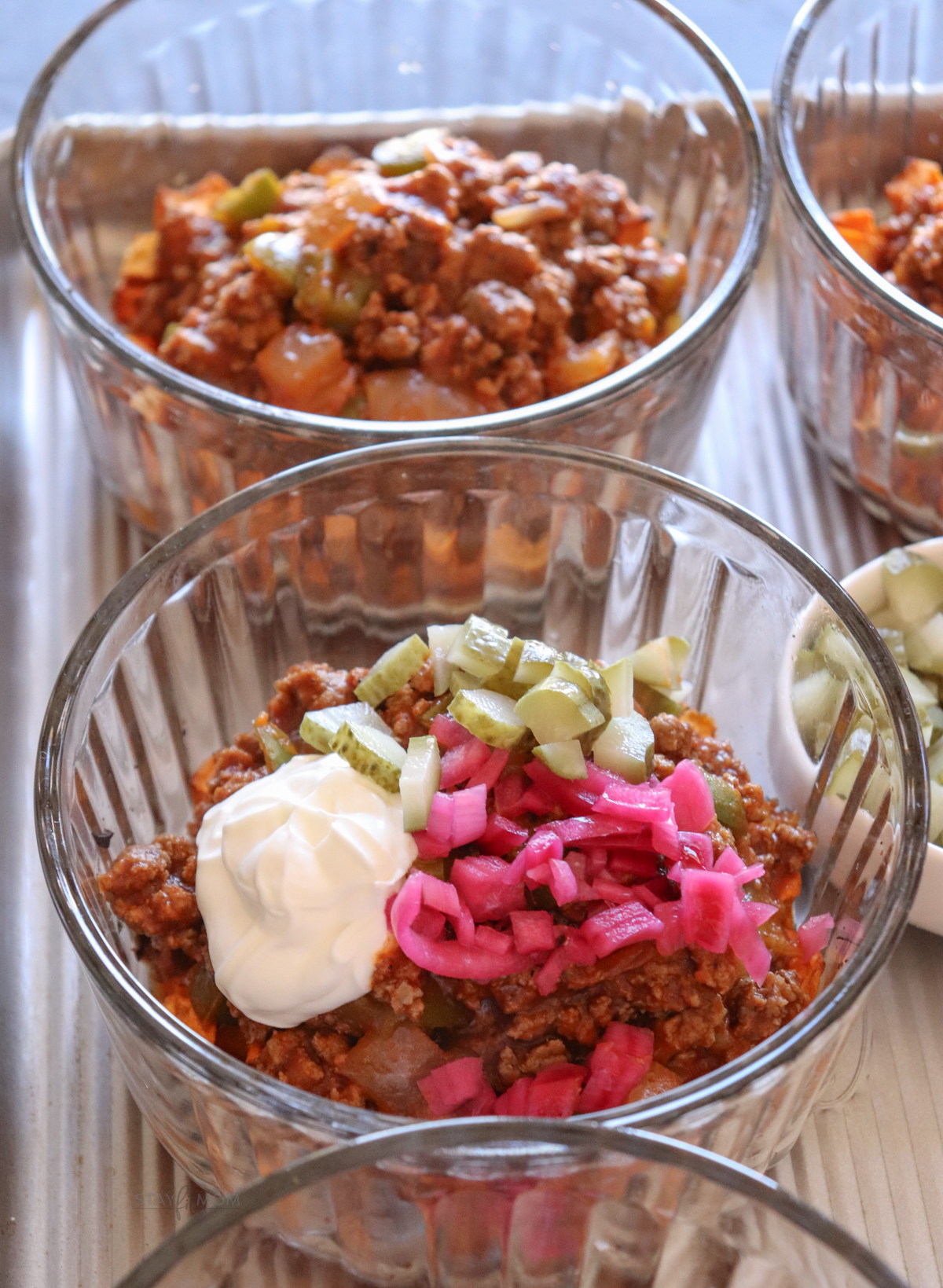 Sloppy Joe Bowls with visible sweet potato, ground beef mixture, greek yogurt, diced pickles, and pickled onions.