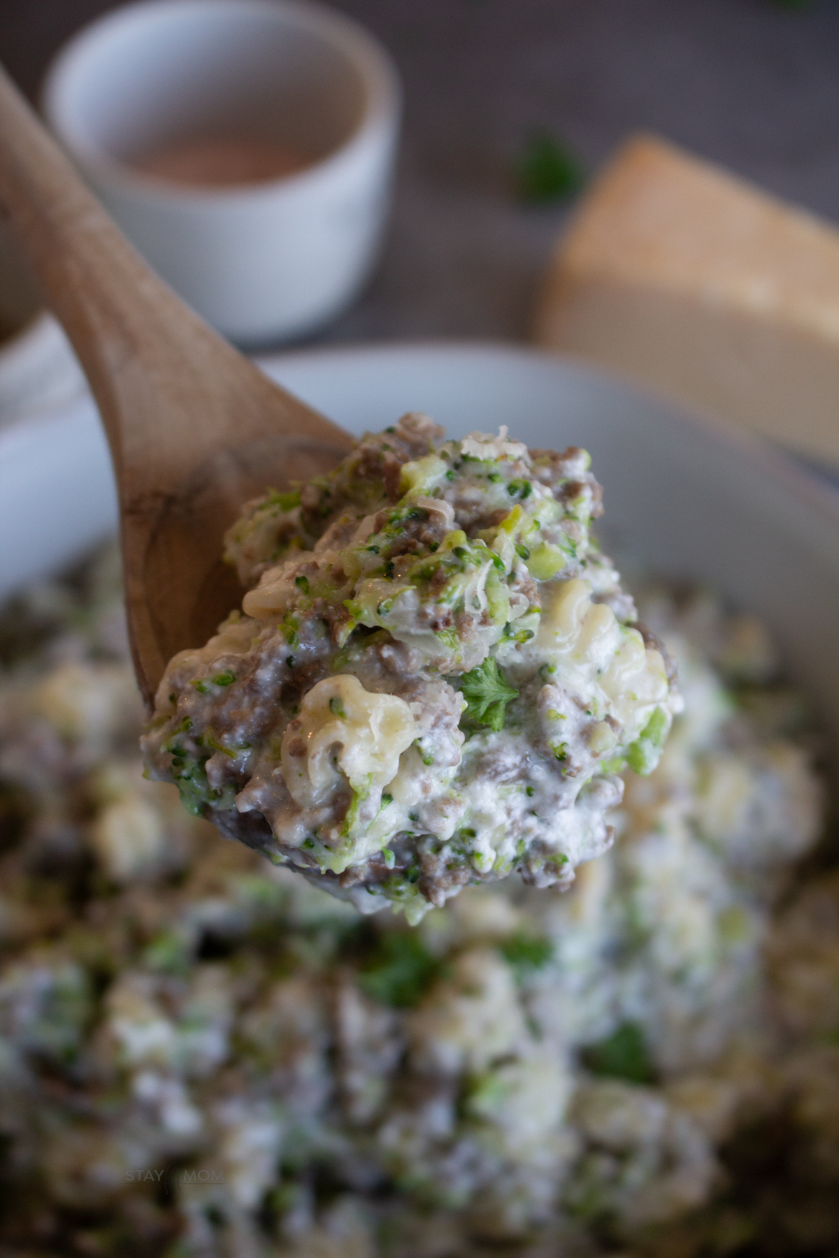 The perfect bite of Beefy Alfredo Mac showing a spoon loaded with pasta, broccoli, ground beef, and a creamy sauce.