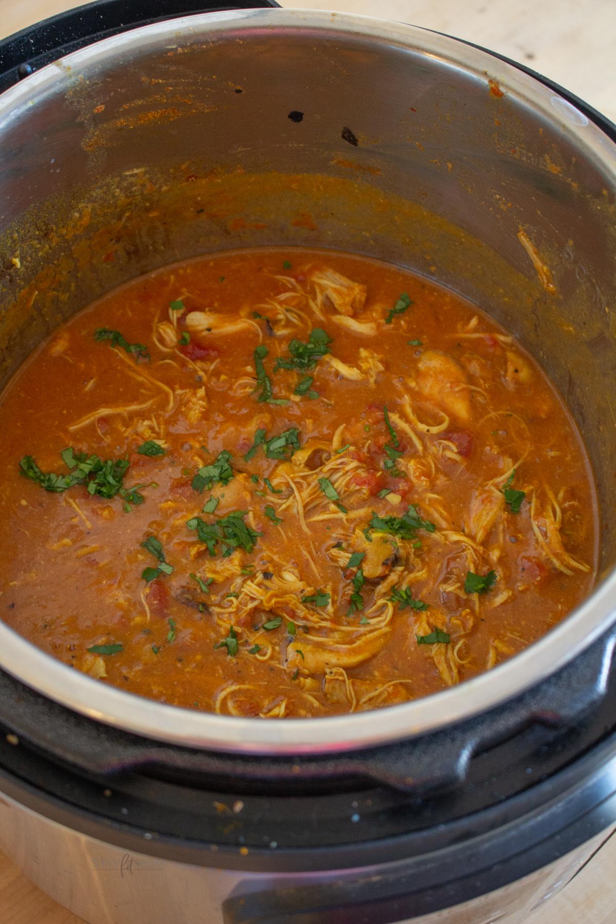 Butter chicken in instant pot showing shredded chicken in sauce inside Instant Pot.