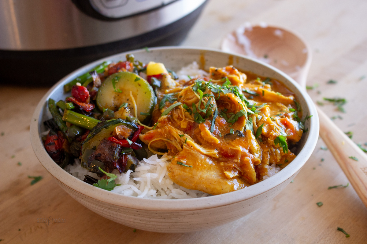 Butter chicken showing sauce with chicken and veggies over rice.