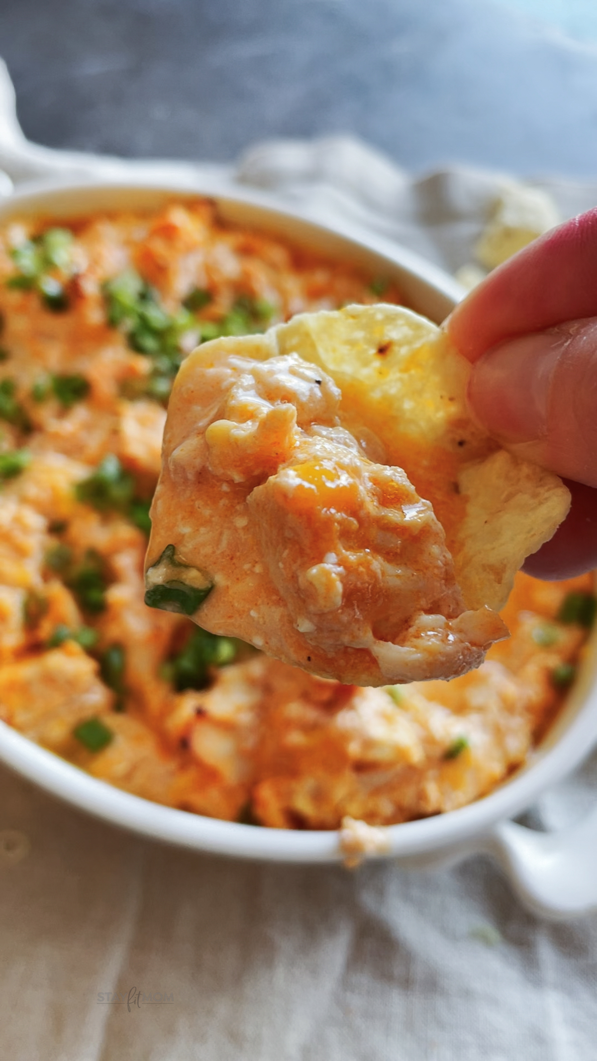 Buffalo Chicken Dip showing a chip loaded with dip.