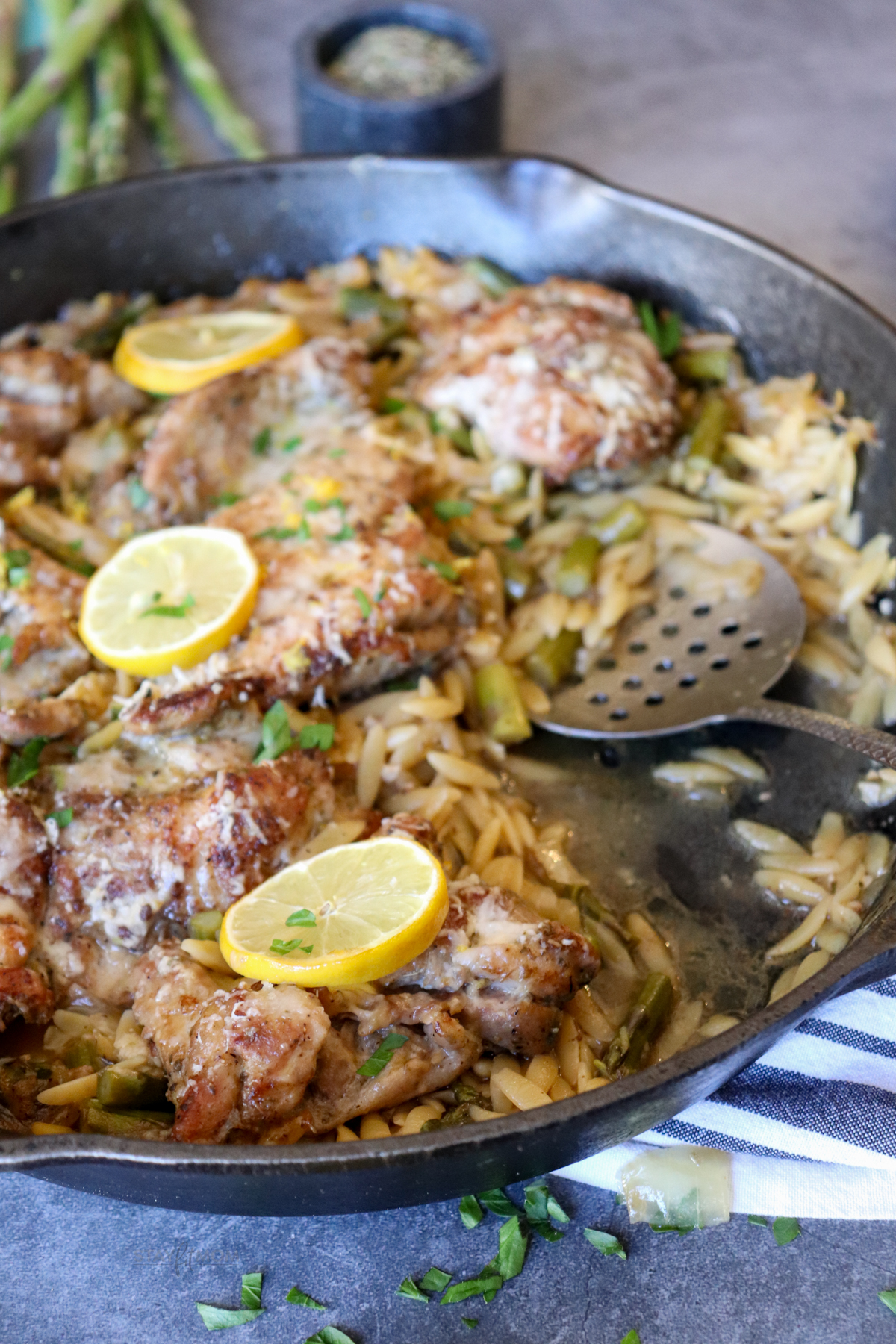 One Dish Lemon Chicken Orzo image showing orzo topped with chicken and sliced lemons.