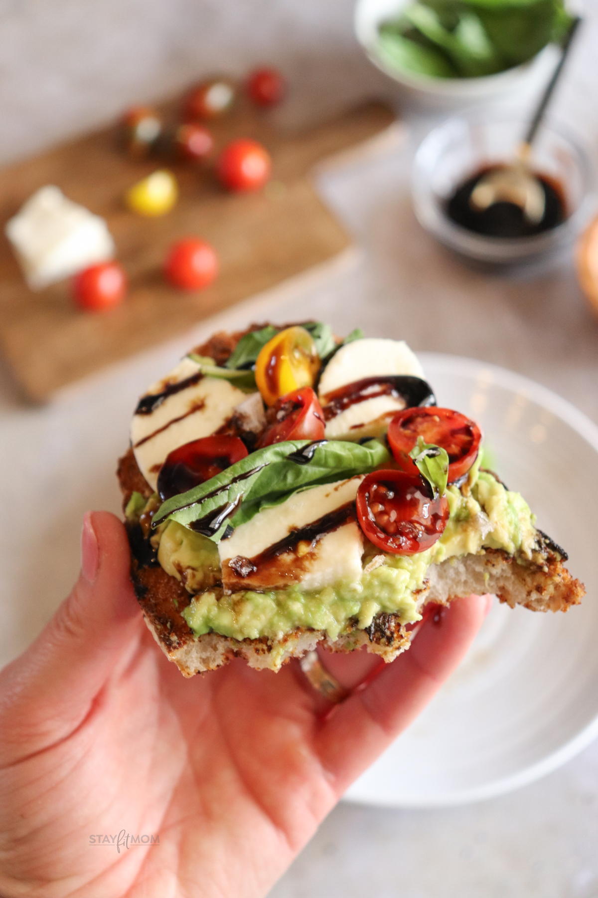 Tomato Basil Sourdough Toast showing completed slice with visible avocado, cherry tomatoes, fresh mozzarella, fresh basil, and a balsamic glaze drizzle.