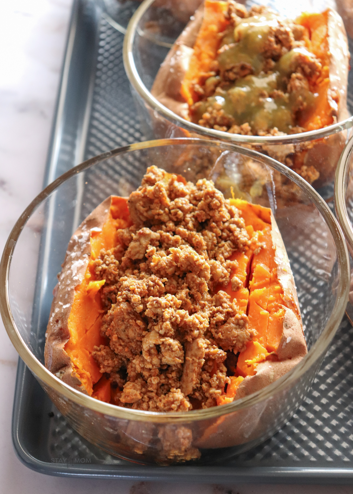 Baked Sweet Potato Bowls showing glass meal prep bowls with cooked sweet potatoes stuffed with seasoned ground turkey.