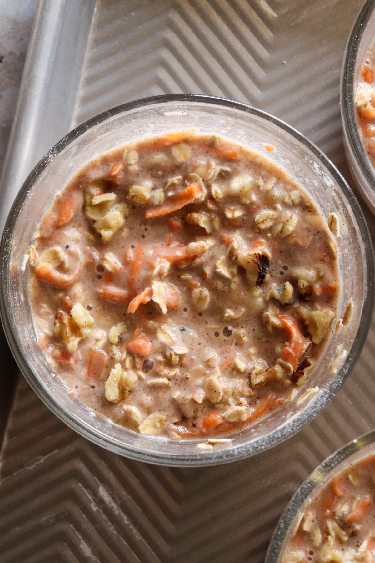 Carrot cake baked oats mixed in meal prep bowl and ready to be baked with visible oats and shredded carrots.