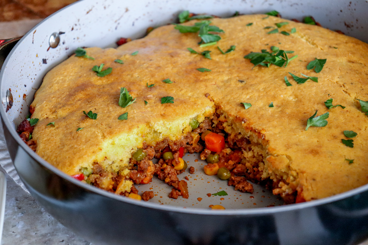 Cowboy Cornbread Casserole showing pan with one piece missing showing cornbread and casserole filling.