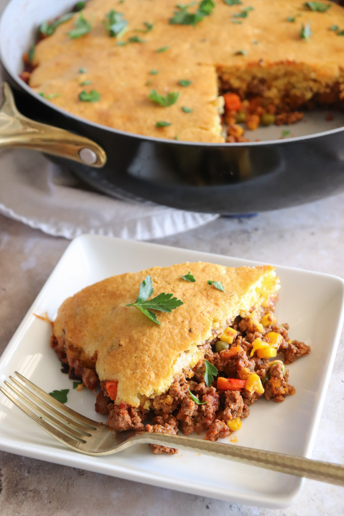 Cowboy Cornbread Casserole showing a slice of the meal with the pan in the background.