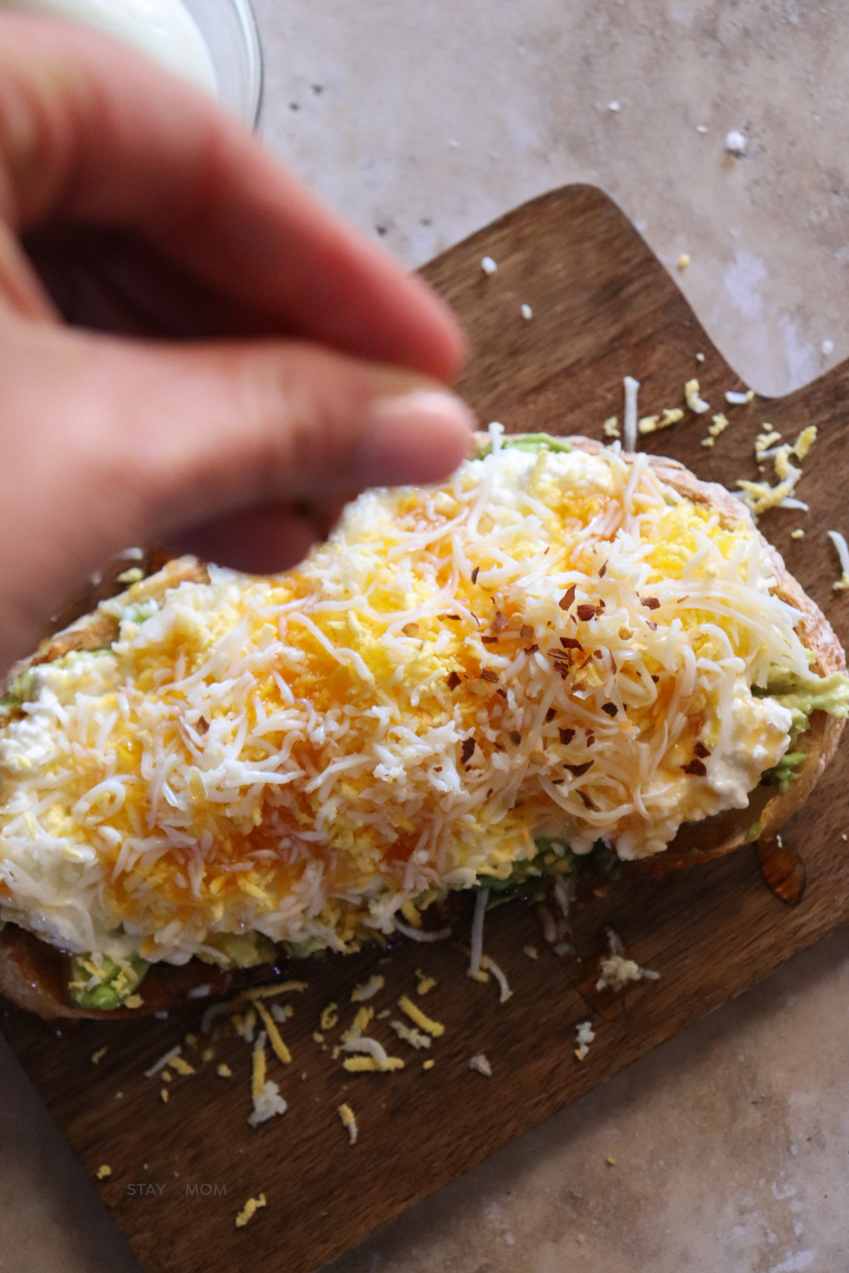 Shredded Egg Sourdough Toast with red pepper flakes being sprinkled on top.