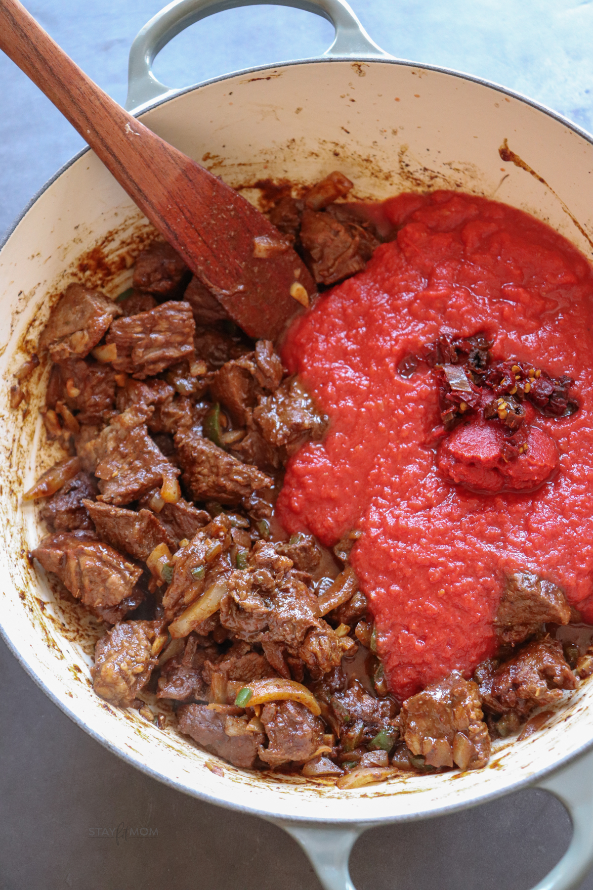 Texas Chili showing tomato sauce being added to cooked chuck roast.