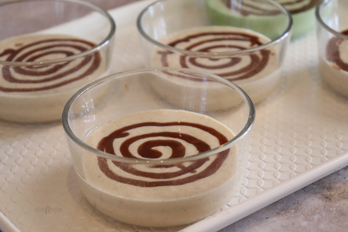 Cinnamon Roll Pancake Bowls showing glass bowls willed with pancake batter and swirled with cinnamon, ready to be baked.