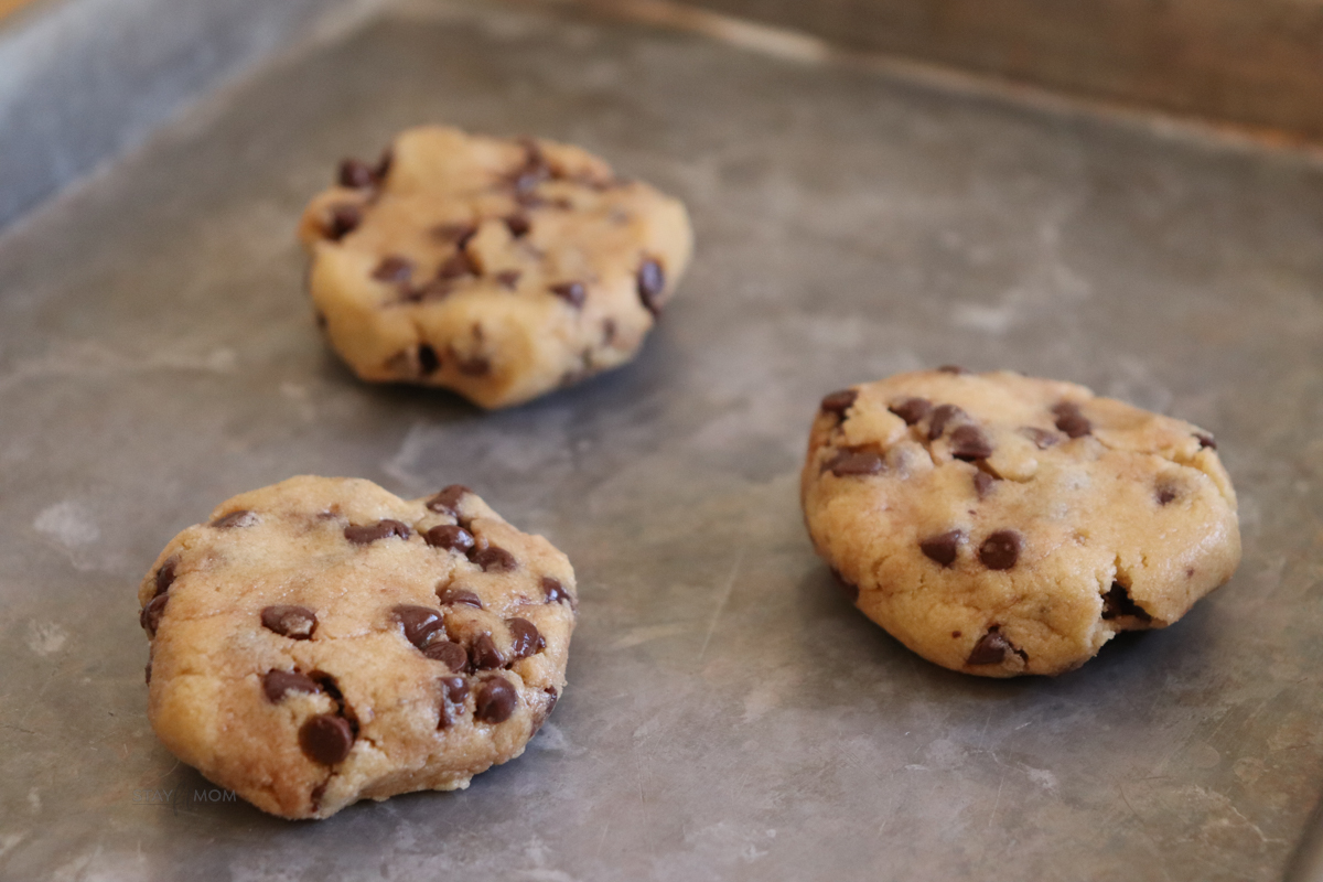 Protein Chocolate Chip Cookies showing cookie dough balls slightly pressed down on baking sheet.