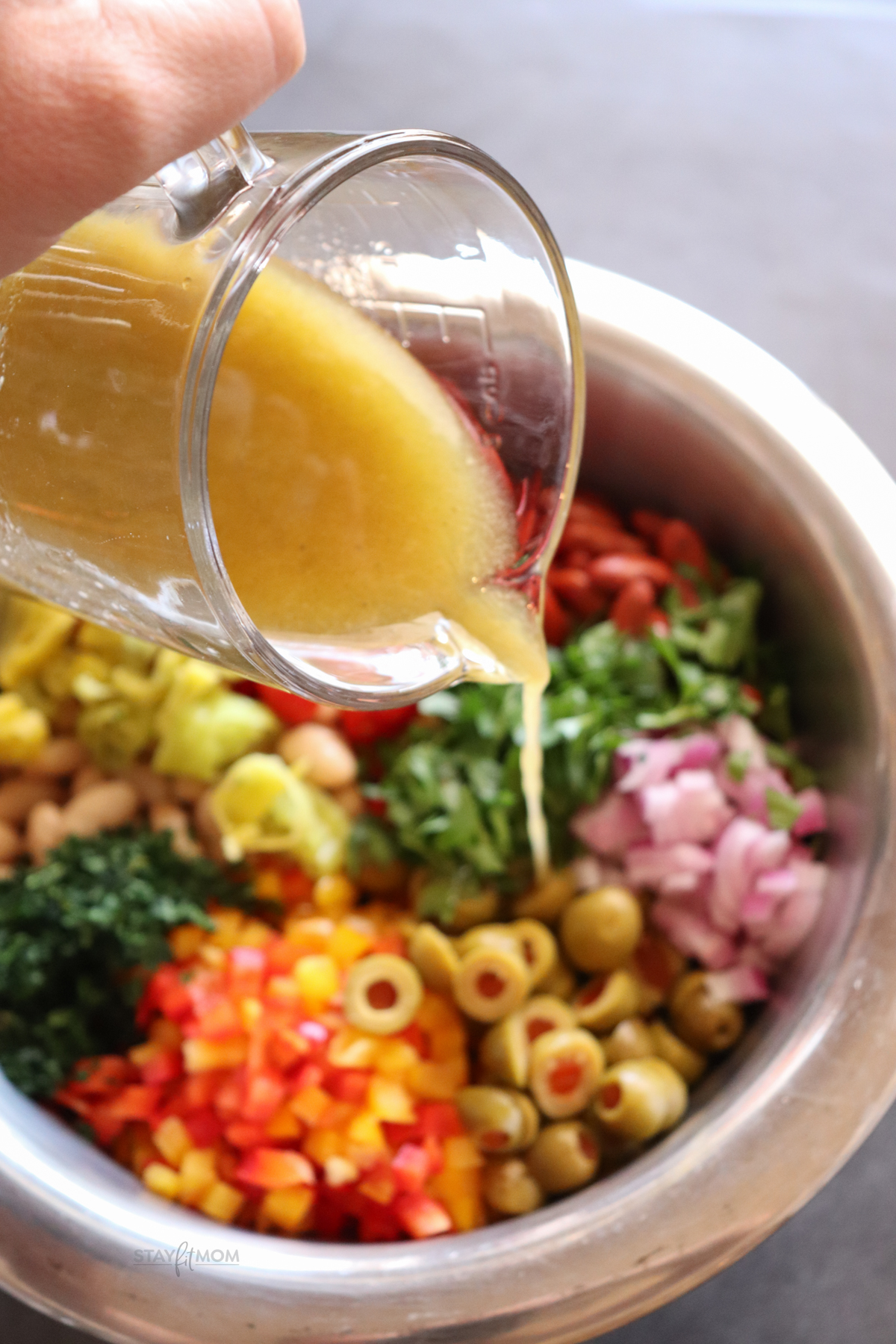 Bean Summer Salad showing bowl with ingredients and vinaigrette being poured on top.