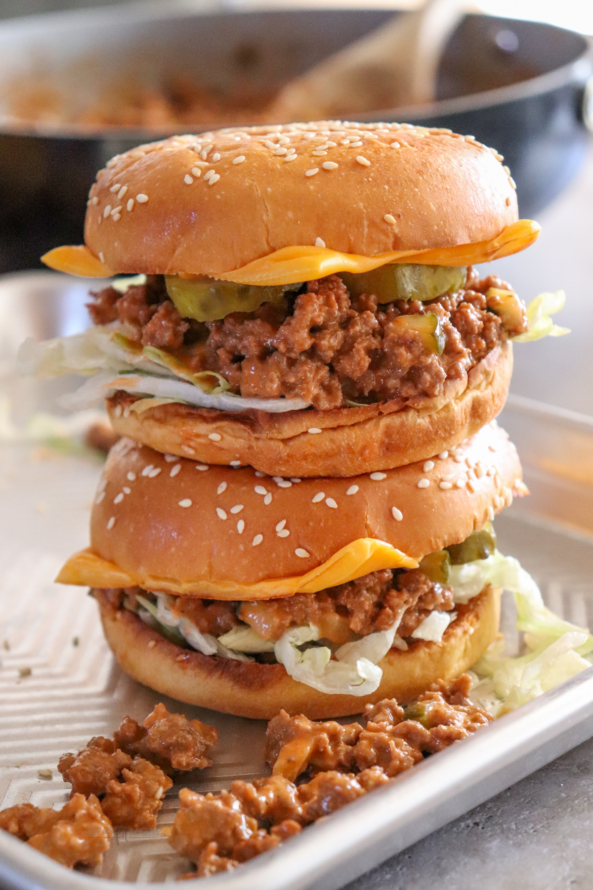 Cheeseburger Sloppy Joes showing completed sandwiches topped with American cheese, lettuce, and pickles.