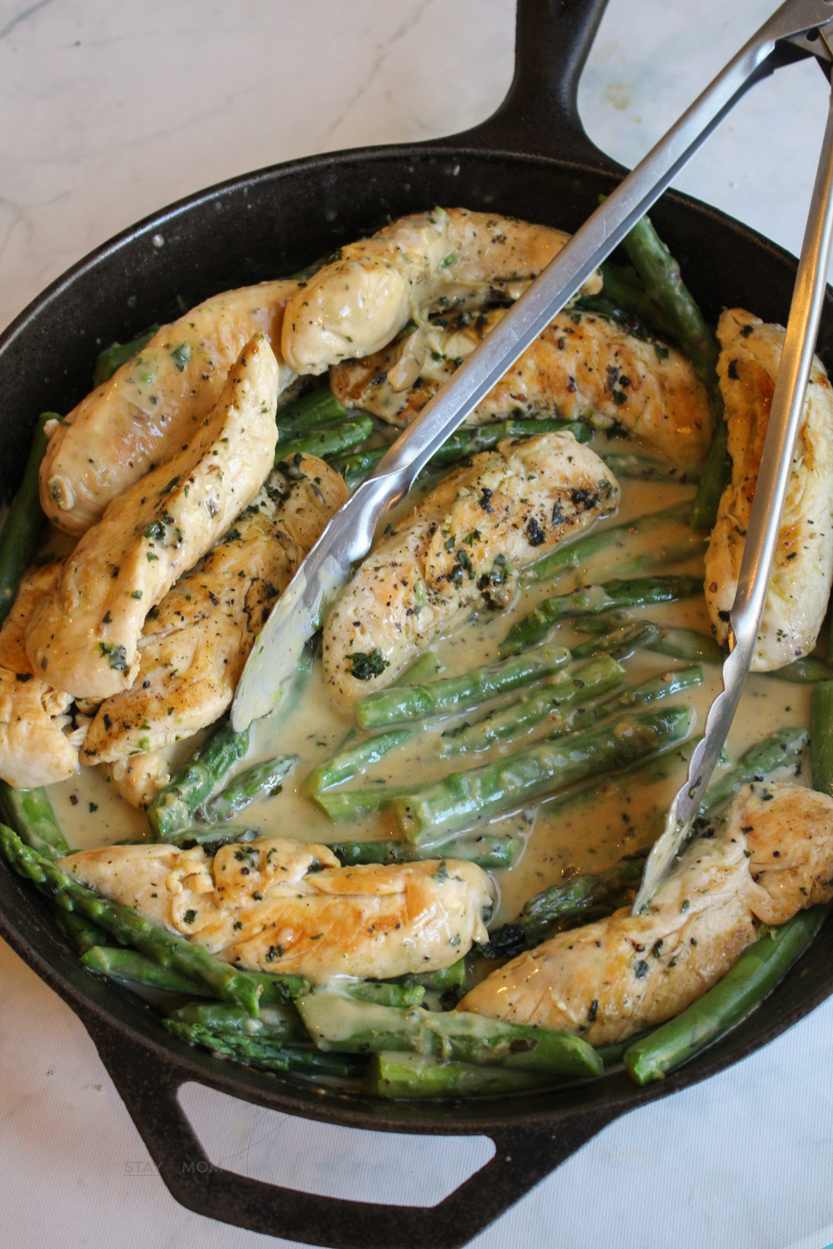 Creamy Garlic Basil Chicken showing completed meal with chicken tenders, asparagus, and a creamy sauce.