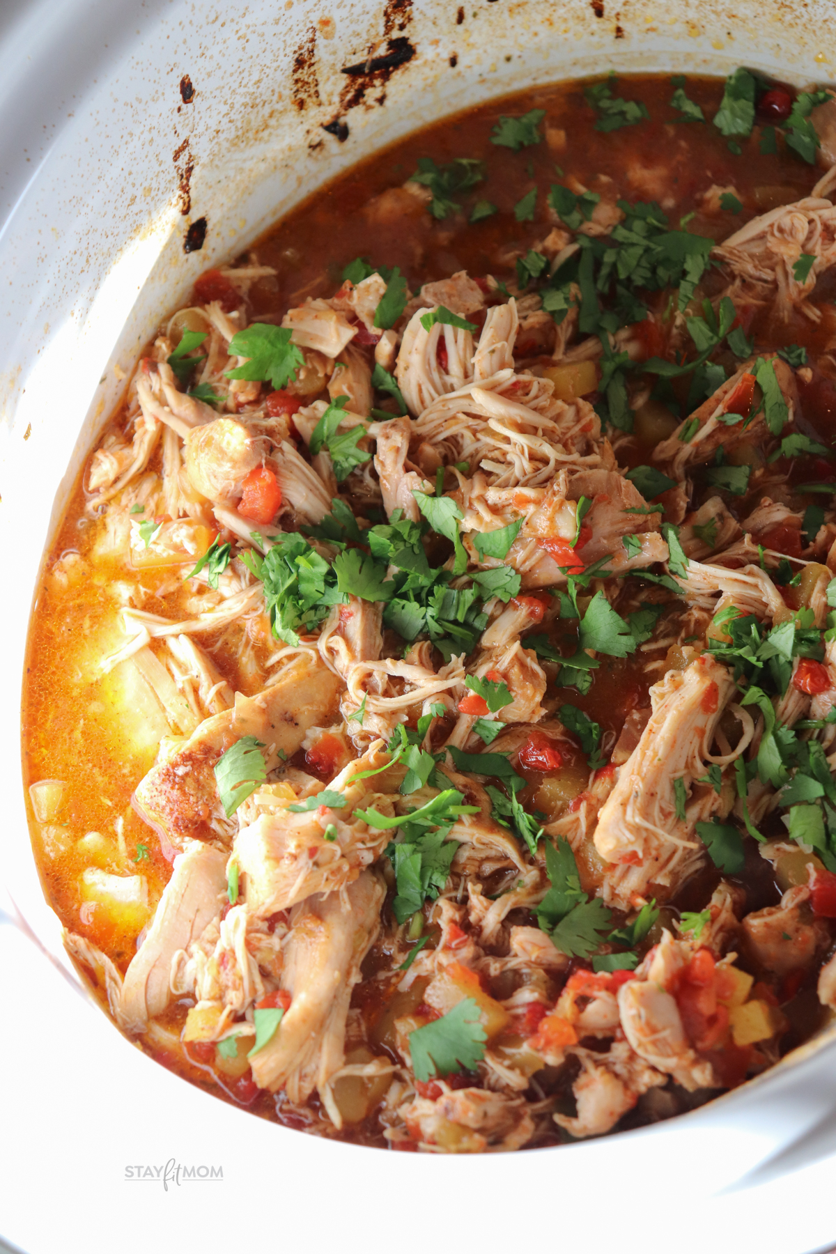 Mango Salsa Chicken showing completed recipe in slow cooker with visible shredded chicken, mango, salsa, juices, and topped with cilantro.