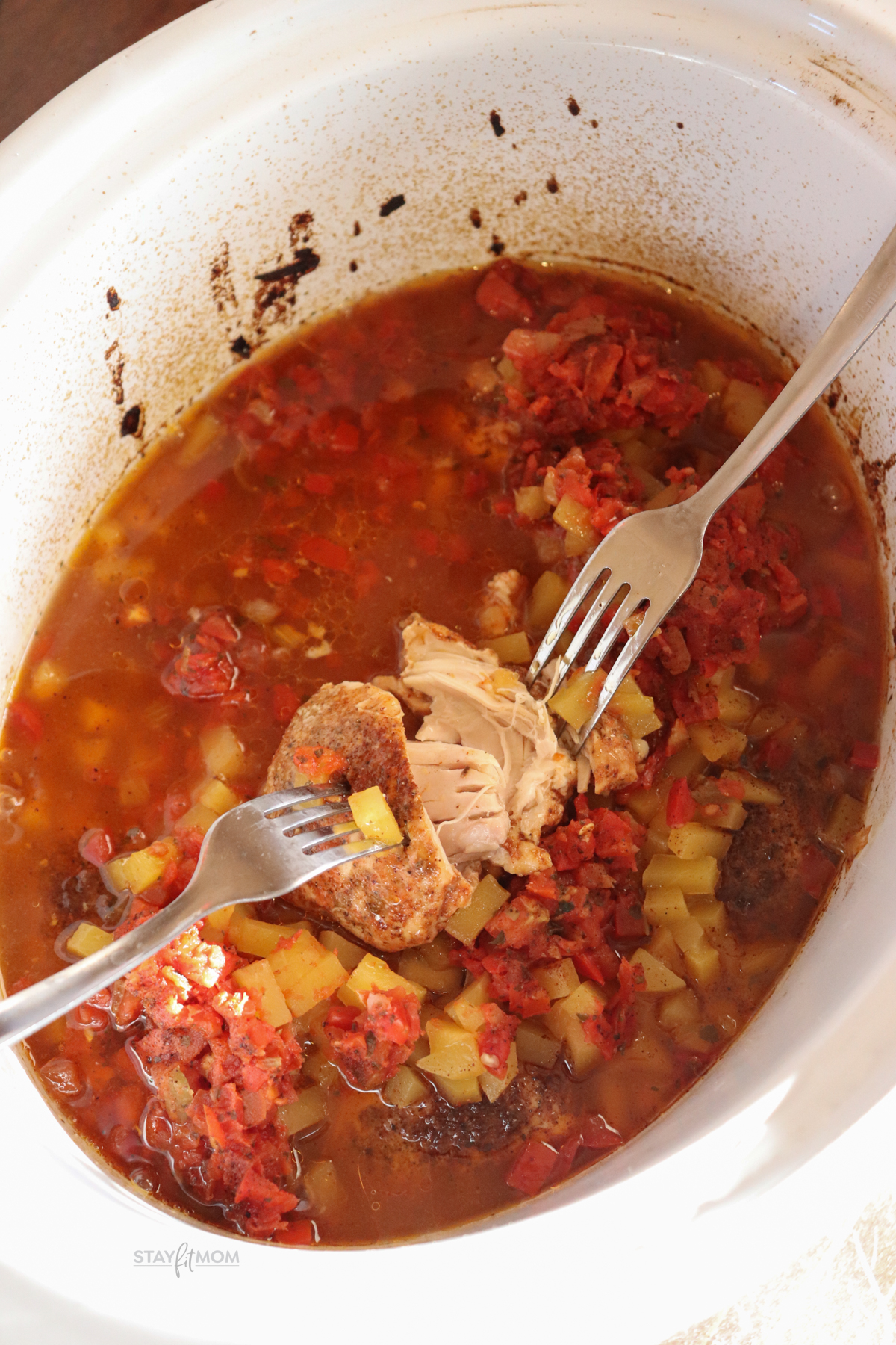 Mango Salsa chicken showing chicken being shredded in the juices with forks.