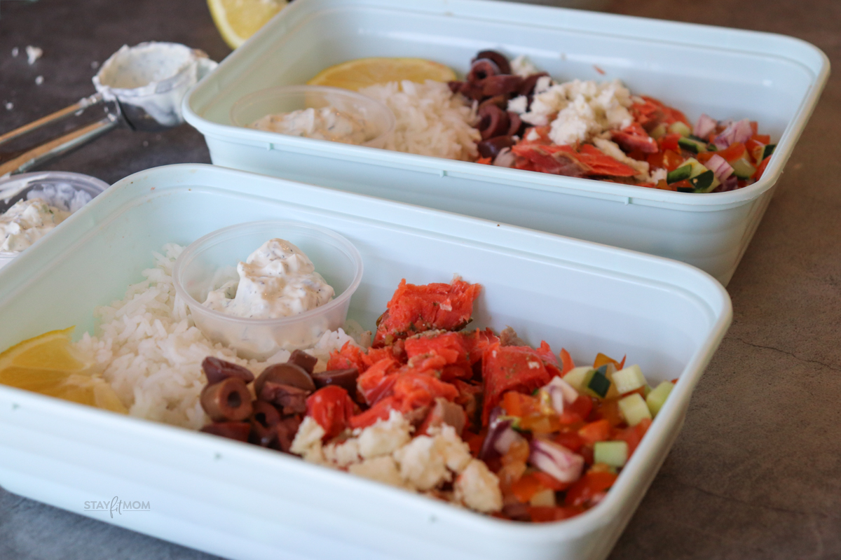 Salmon Greek Bowls showing completed meal prep with visible rice, salmon, olives, tzatziki, and sauce.