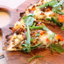 breakfast pizza sliced on a wood cutting board.