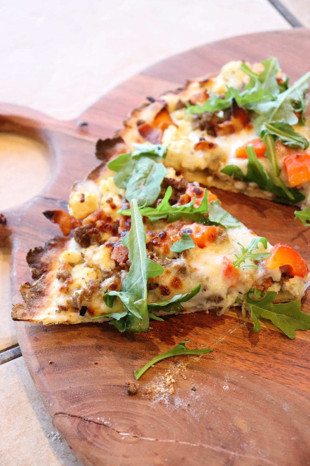 breakfast pizza sliced on a wood cutting board.