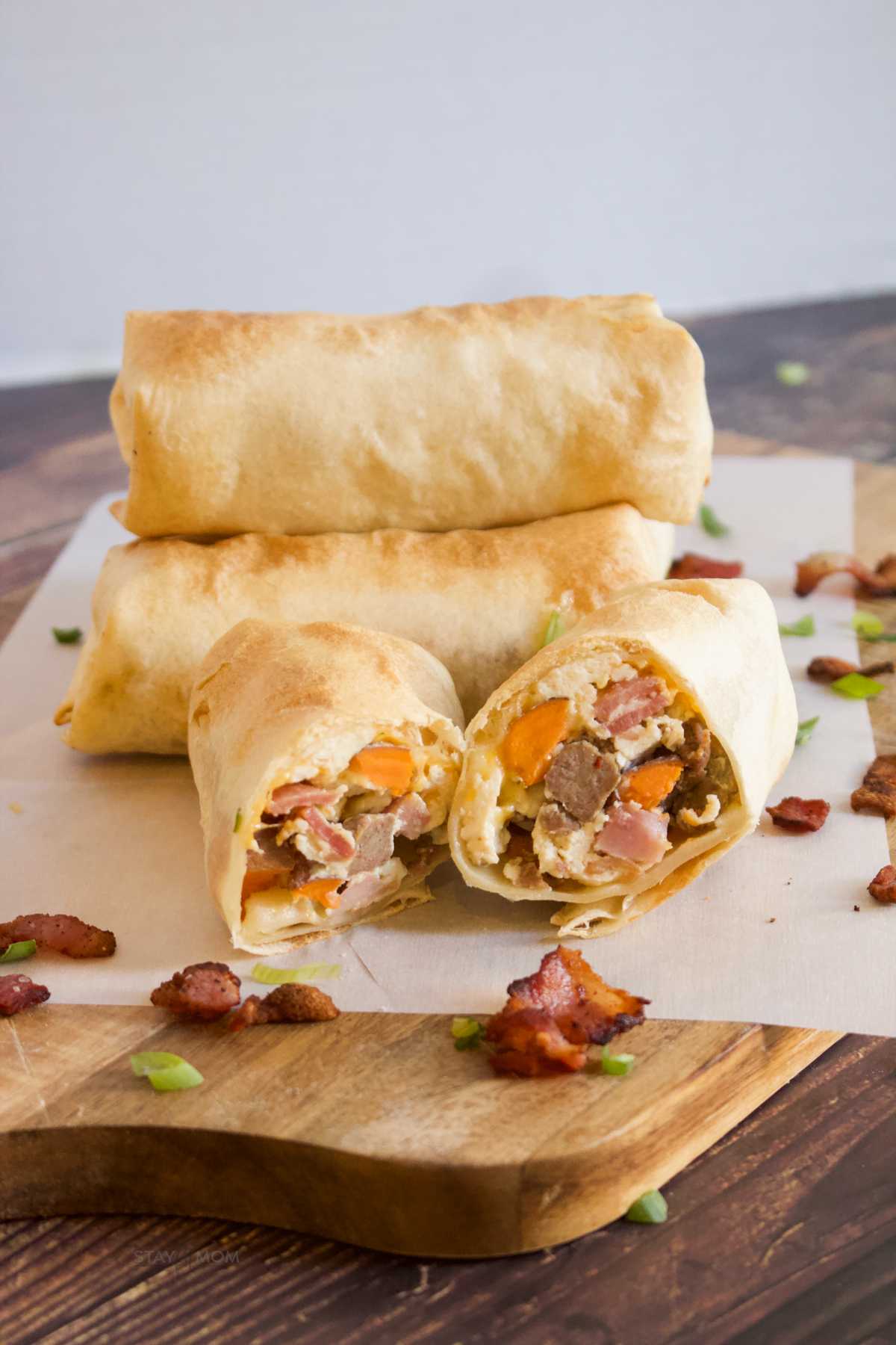 Meat Lovers Breakfast Burritos showing completed Burritos and one cut in half to show inside with visible turkey sausage, bacon, ham, and eggs.