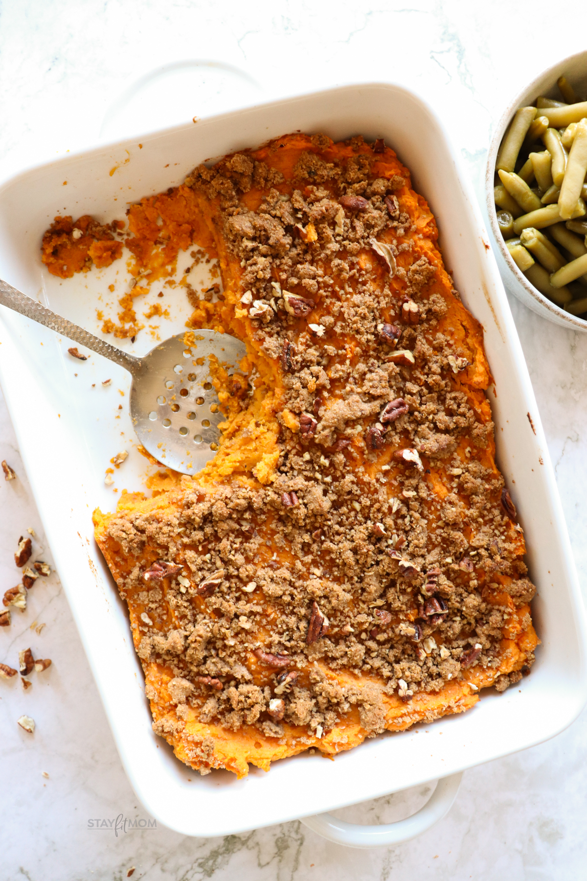 Sweet Potato Casserole showing completed meal with a scoop taken out, with visible sweet potato casserole topped with a pecan topping.