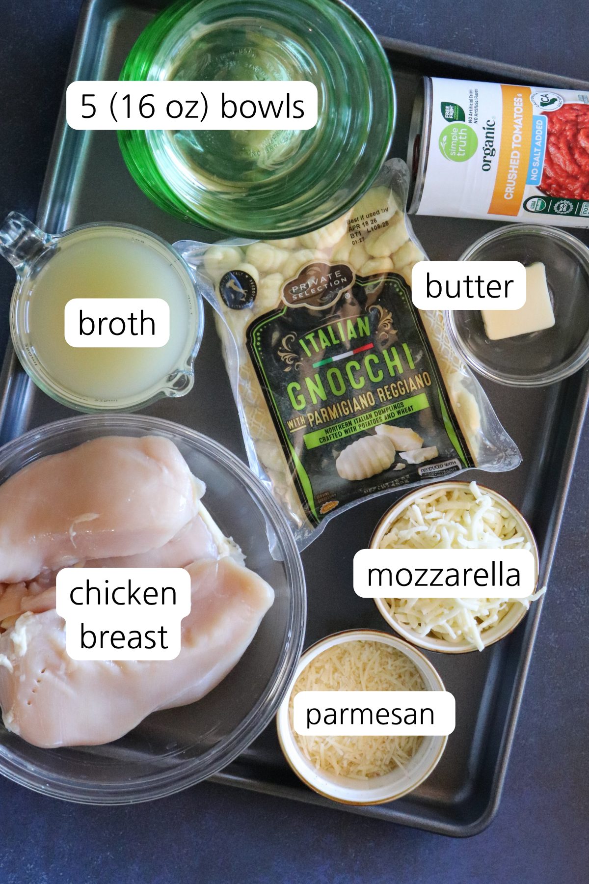Overhead shot of ingredients for Chicken Parmesan Gnocchi Bowls, including chicken, gnocchi, marinara sauce, and cheeses arranged on a countertop.