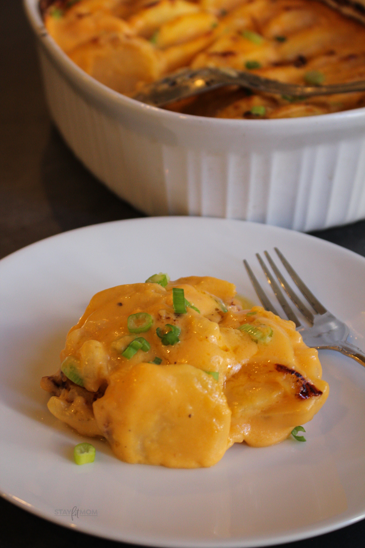 Cheesy scalloped potatoes topped with scallions ready to serve on a plate.