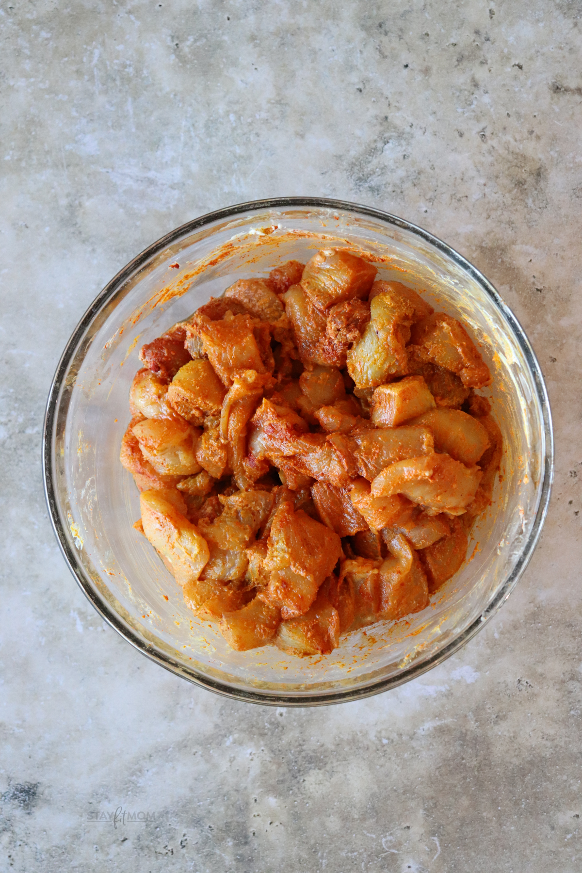 “Diced chicken breast marinating in Greek yogurt, lemon juice, and tikka masala spices in a glass bowl for a healthy high-protein tikka masala recipe.”