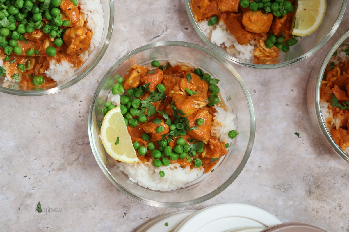 “Macro-friendly chicken tikka masala served over rice in a white bowl, creamy tomato sauce coating tender chicken pieces. High-protein Indian-inspired meal prep recipe.”