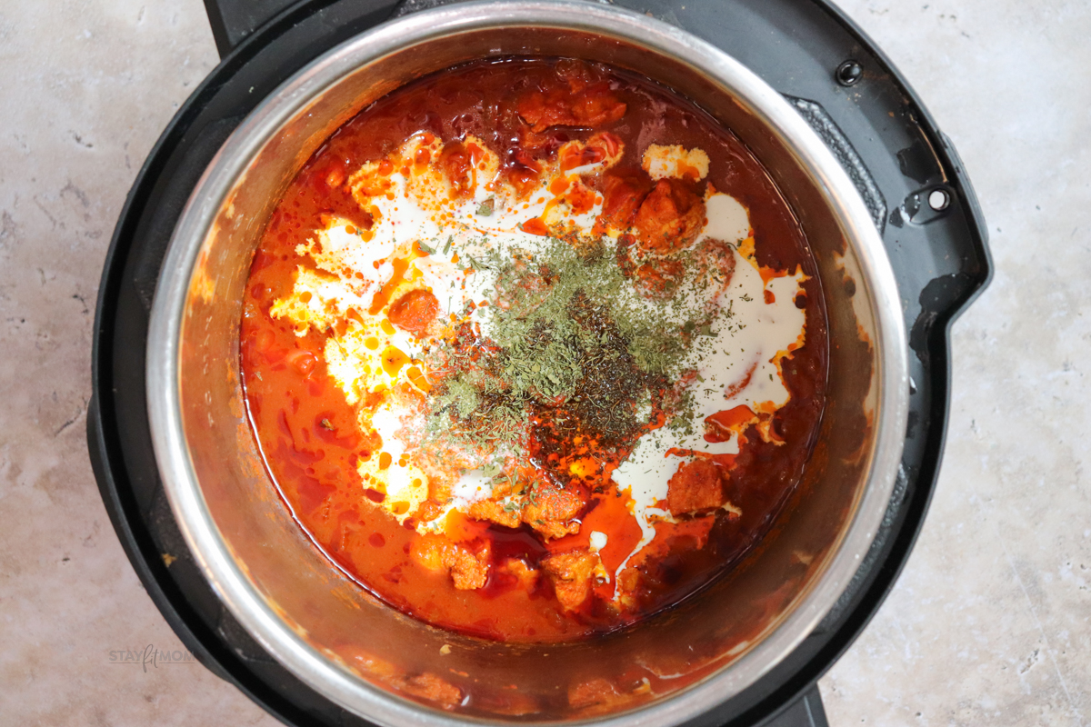 “Heavy cream being stirred into cooked tikka masala to create a rich, silky sauce for this high-protein meal prep dish.”