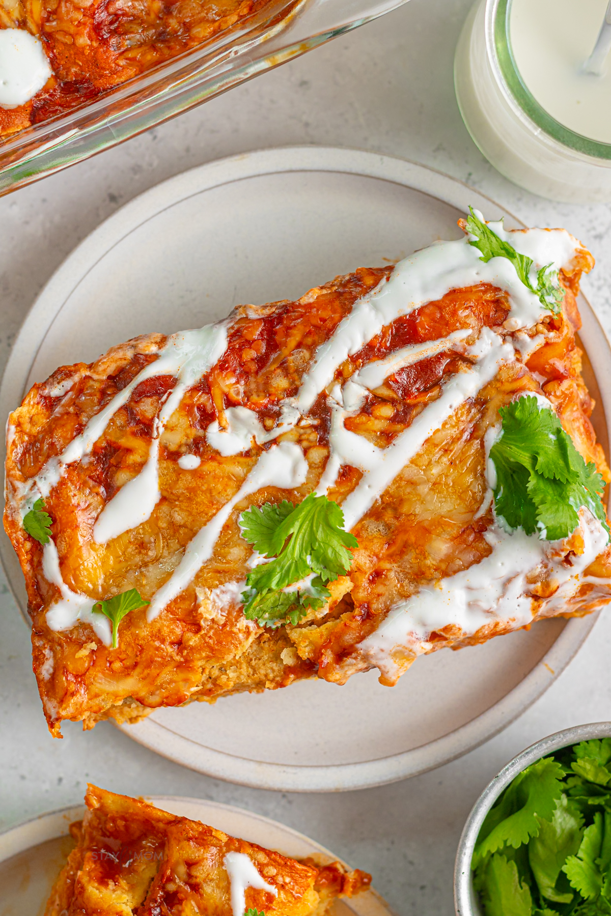Two cheesy pork enchiladas topped with melted Mexican cheese and red enchilada sauce on a plate. High-protein, macro-friendly enchilada recipe.