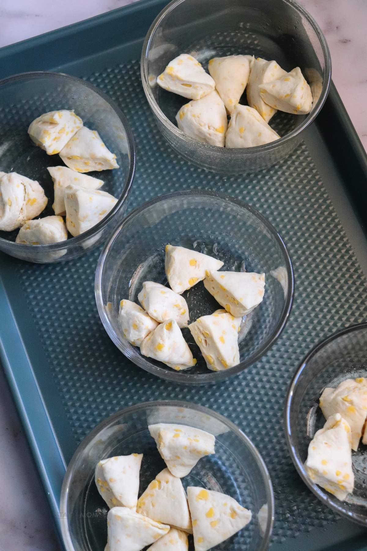 Biscuits and Gravy Casseroles showing 5 oven-save containers on a baking sheet with cut up biscuits in the bottom.