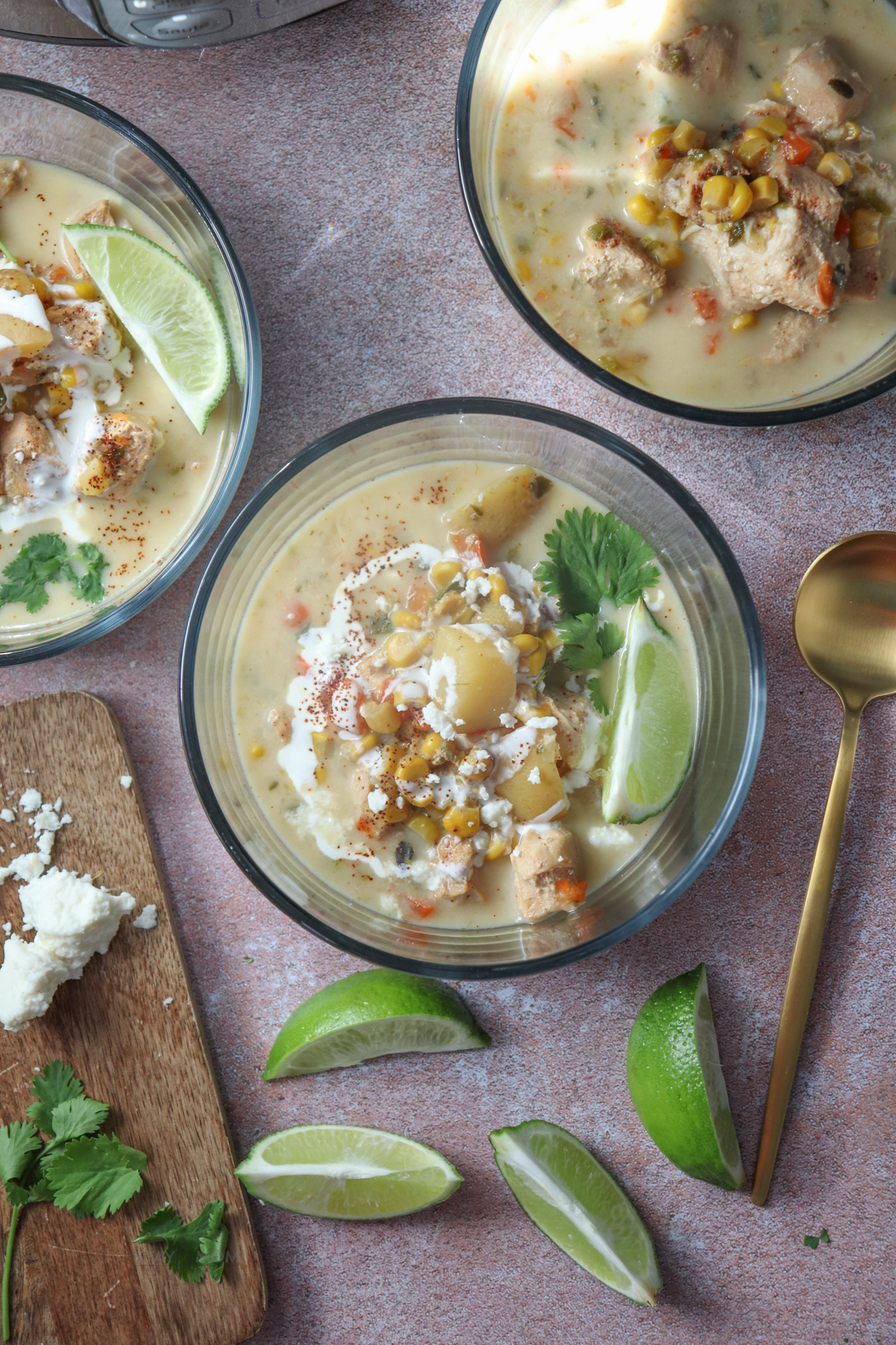 Chicken Street Corn Casserole showing 3 servings in small glass bowls with visible corn, potatoes, chicken, broth, and a lime wedge.