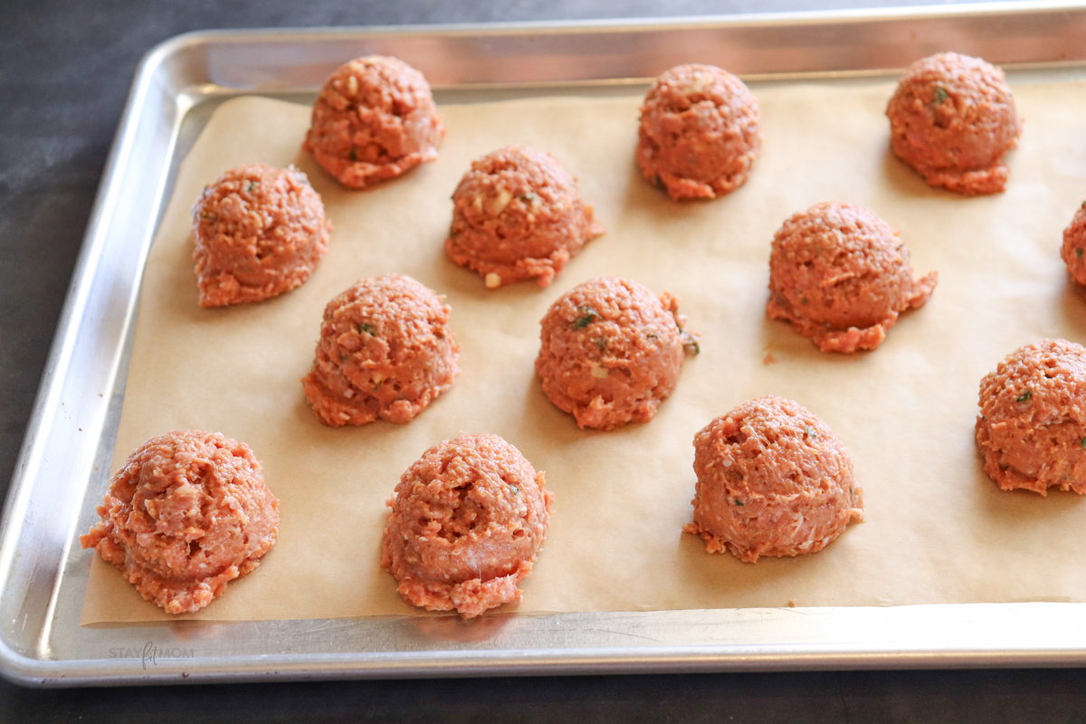Thai Turkey Meatballs showing meatballs scooped onto a parchment lined baking sheet ready to go in the oven.