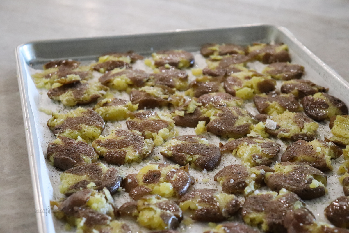 A full sized sheet pan showing smashed, salted crispy roasted potatoes.