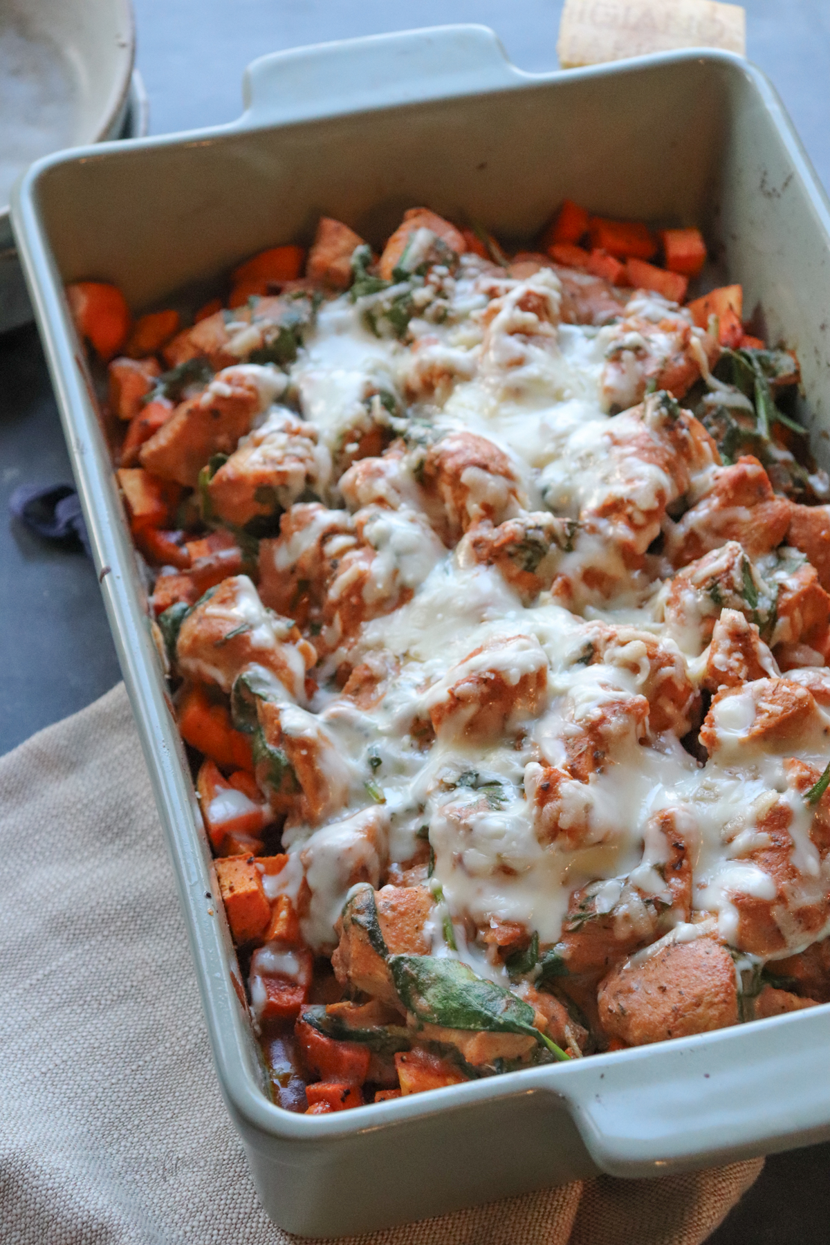 Cajun Chicken & Sweet Potato Casserole showing completed recipe in a casserole dish with visible sweet potatoes, spinach, chicken, sauce, and topped with melted cheese.