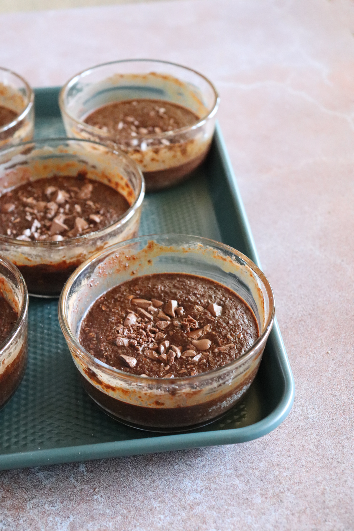Chocolate baked oats showing sheet pan with 5 glass bowls containing chocolate baked oats.