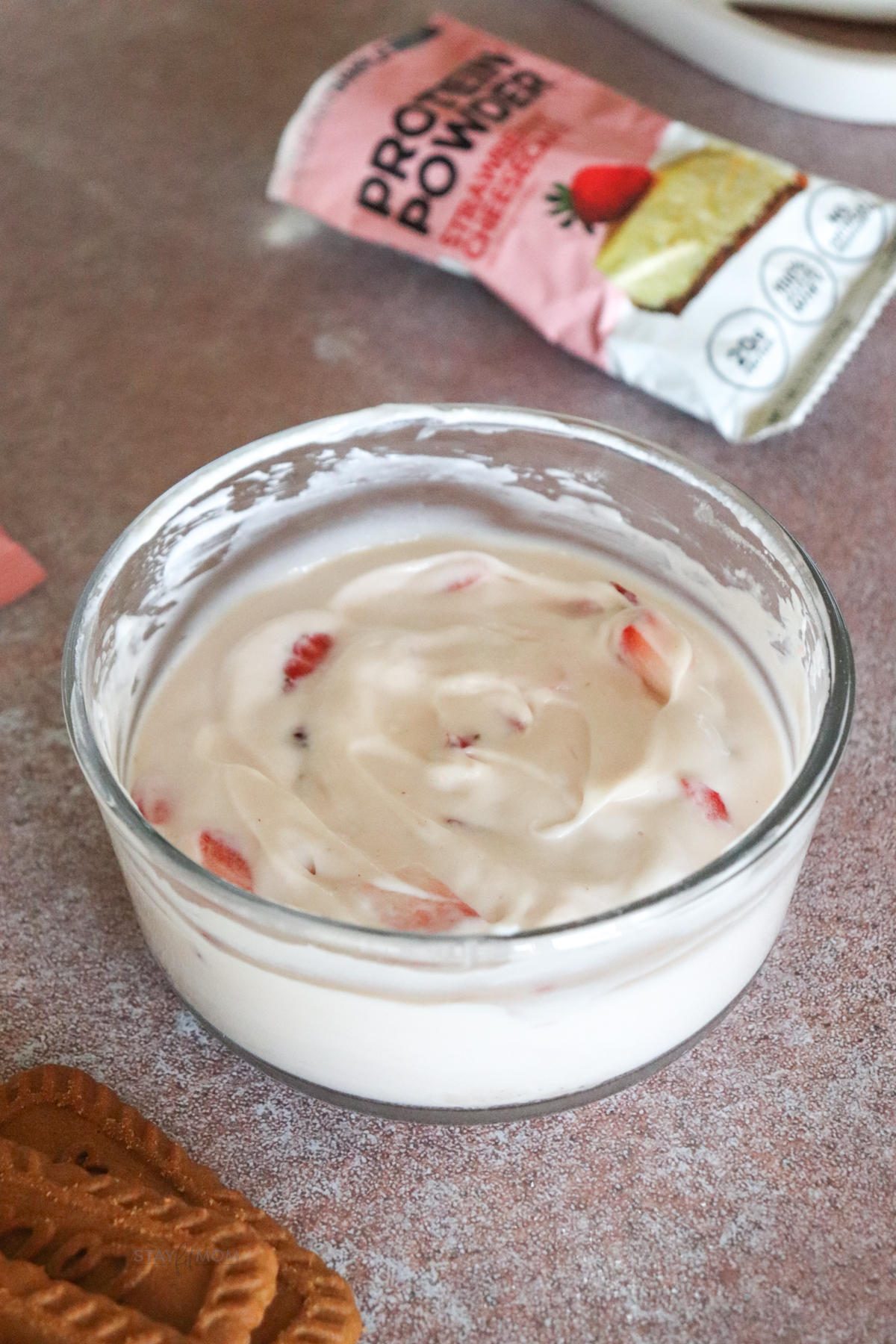 Small glass bowl showing strawberries stirred into Greek yogurt and protein powder.