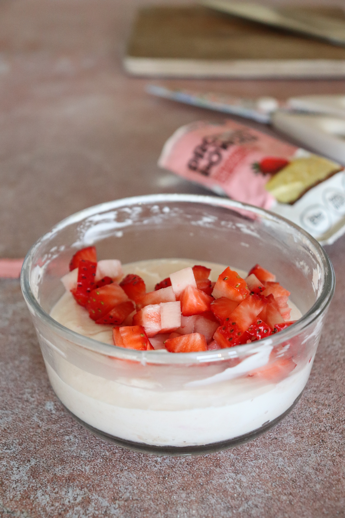 Small glass bowl filled with Greek yogurt and protein powder stirred in and topped with strawberries.