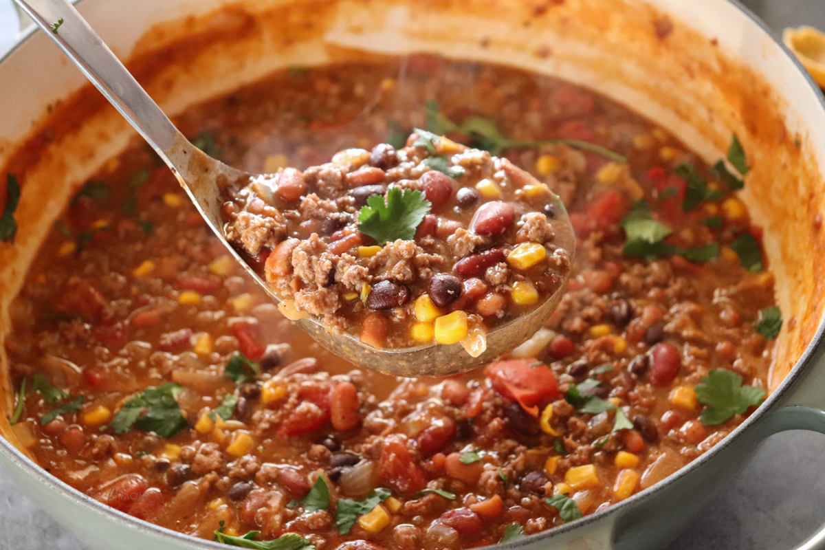 Taco Soup 2.0 finished recipe with a ladle showing a spoonful of the soup.