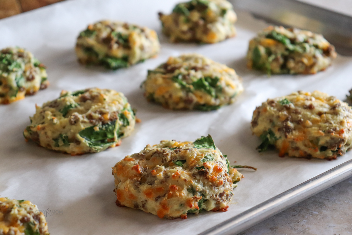 Cheesy sausage biscuits showing completed recipe with visible spinach, cheese, and crumbled breakfast sausage baked to perfection.