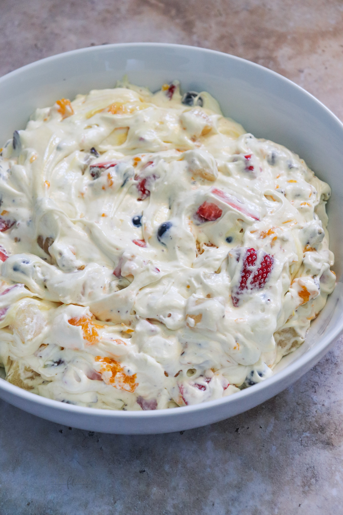Cookie fruit salad showing fruit stirred into pudding mixture.